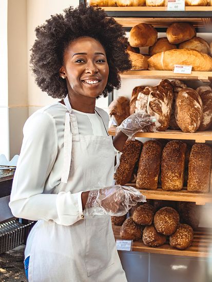 Woman smiling whilst wearing see through gloves and handling bread
